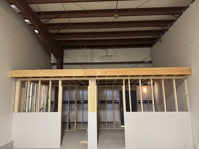Bay 2 interior showing the mezzanine framing built above the office and bathroom walls