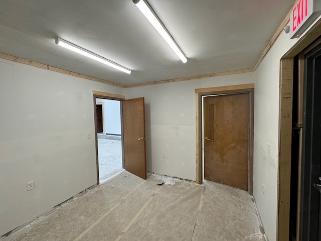 Bay 2 interior with a personnel door open to the exterior and a second door to an adjoining room, drywall finished