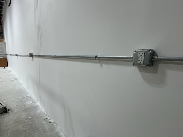 Conduit run with electrical receptacle boxes along a finished interior wall